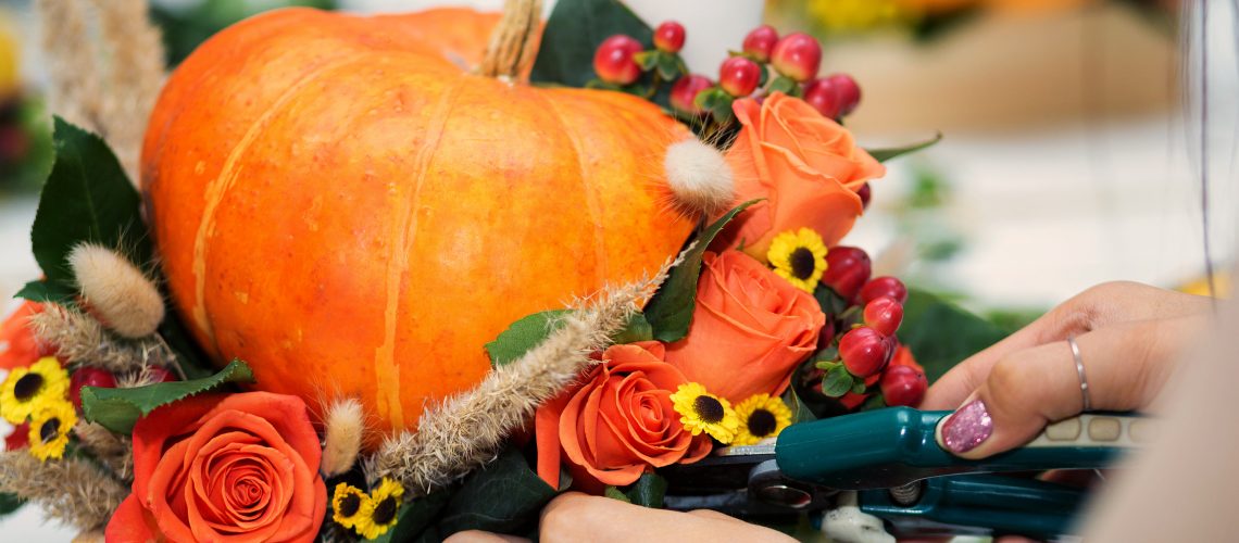 the bright autumn arrangement of flowers and berries in the pumpkin